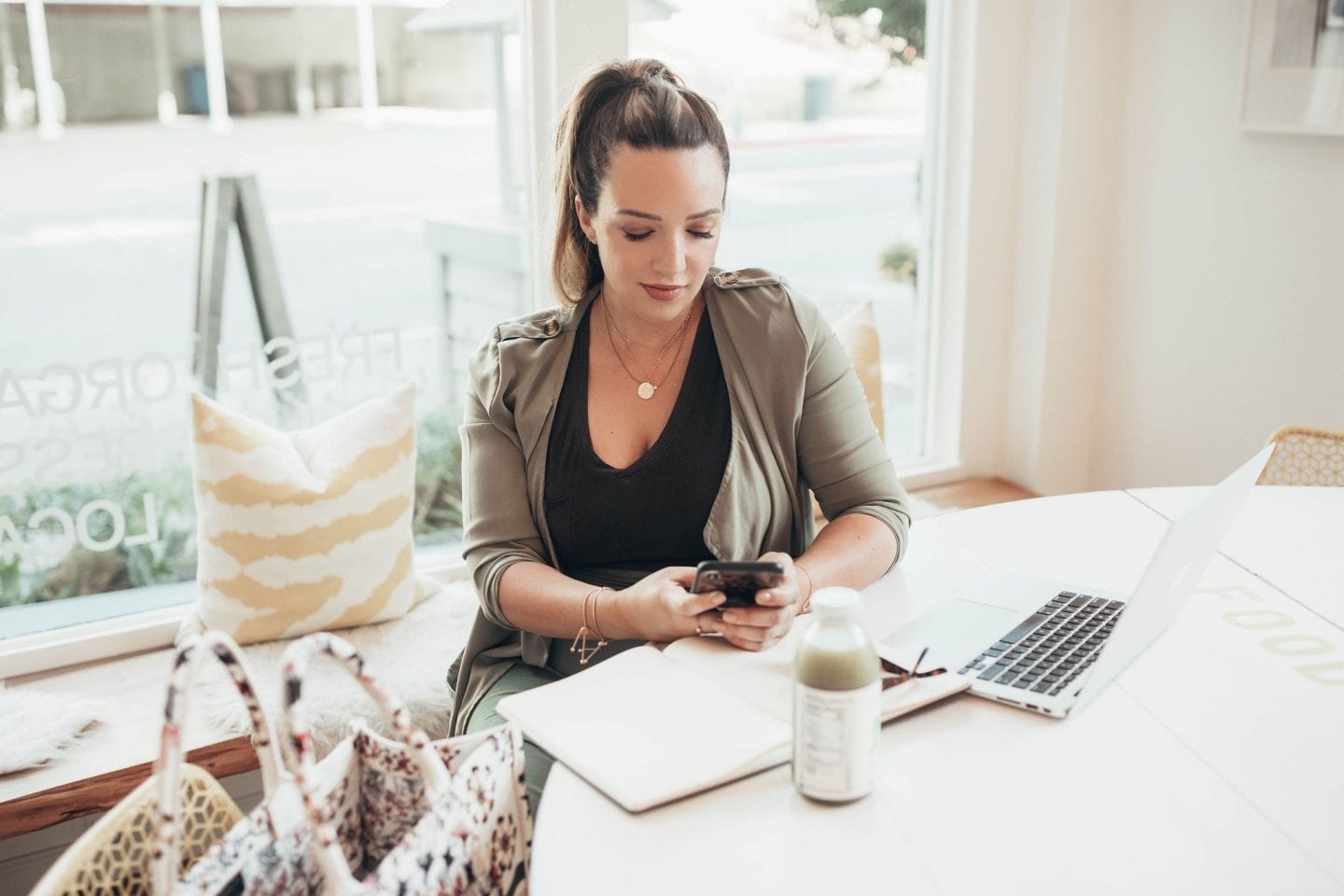 Best Motivational Podcasts by popular San Francisco lifestyle blog, Just Add Glam: image of a woman sitting at a table with her laptop, notebook, and her smartphone. 
