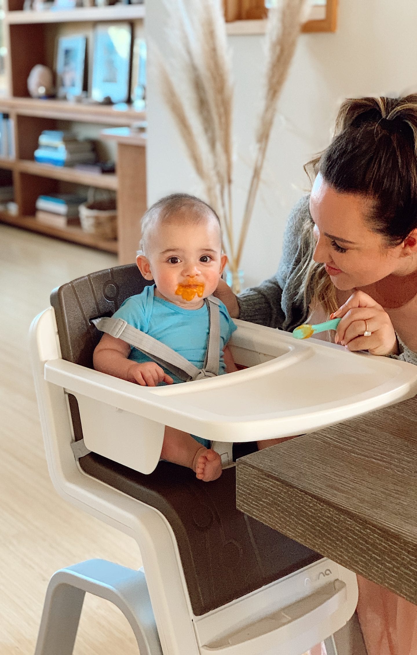 DIY baby food purees | Baby Food by popular San Francisco motherhood blog, Just Add Glam: image of a mom feeding her infant son some baby food as he sits in a Nuna ZAAZ high chair. 