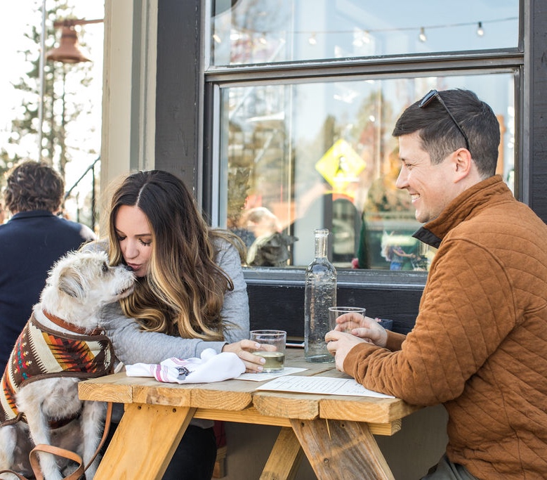 Dog friendly Lake Tahoe | Dog Friendly Restaurants by popular San Francisco lifestyle blog, Just Add Glam: image of a woman kissing her dog while sitting at a wooden picnic table with her husband. 